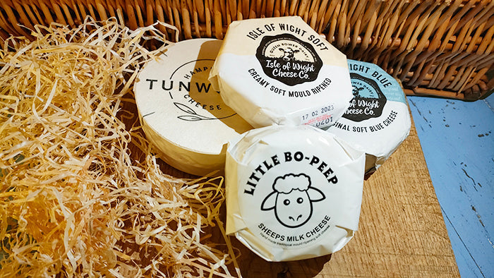 Pile of cylindrical cheeses on a wooden block surrounded by hay