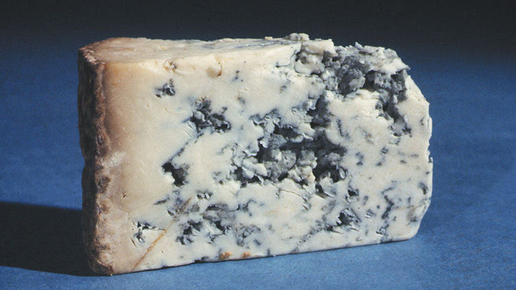 A wedge of blue cheese on a blue surface