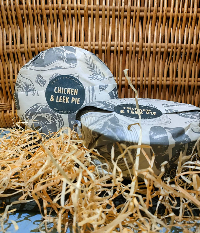 Chicken and leek pies sit before a wicker backdrop with straw in the foreground