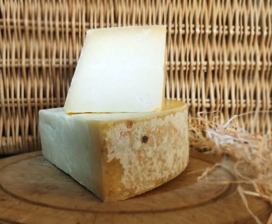 Creamy, award winning cheddar, sat on a cheeseboard, in front of a picnic hamper